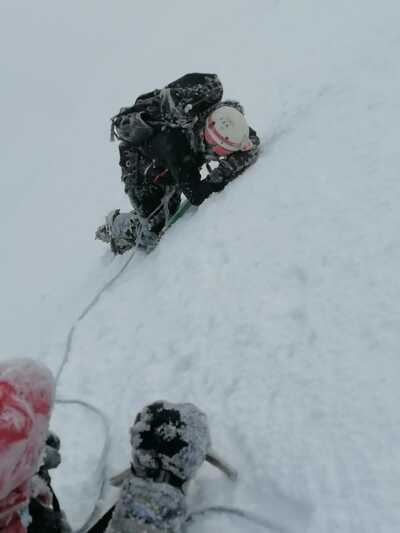 Glacier instructor demonstrating self-arrest technique in freezing conditions on Cotopaxi, Ecuador